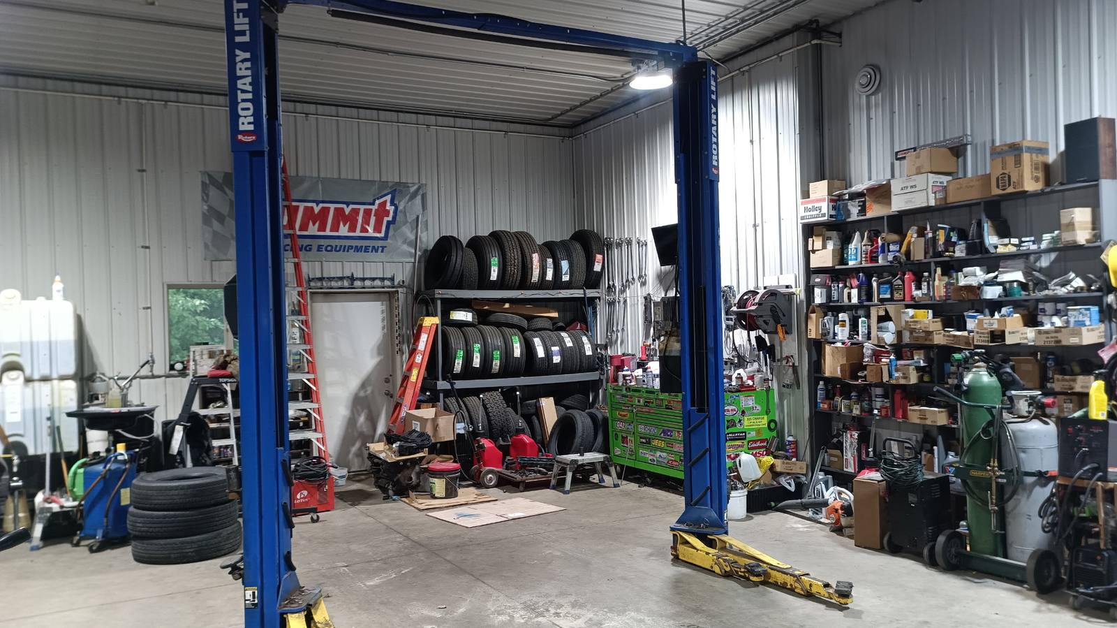 Service bay with Rotary lift, tire racks, and parts shelves