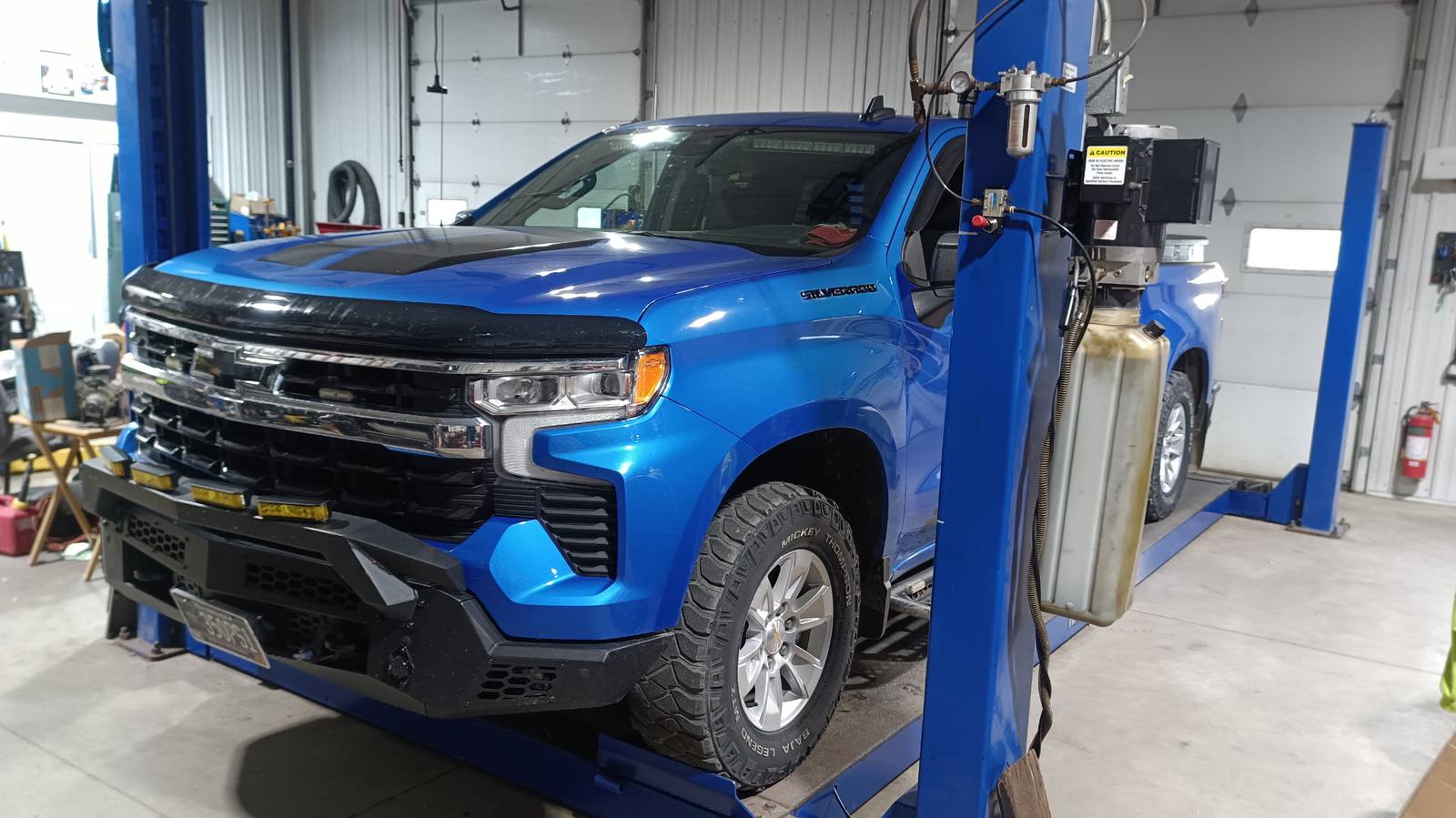 Blue Chevrolet Silverado on a lift inside Midtown Sales and Service